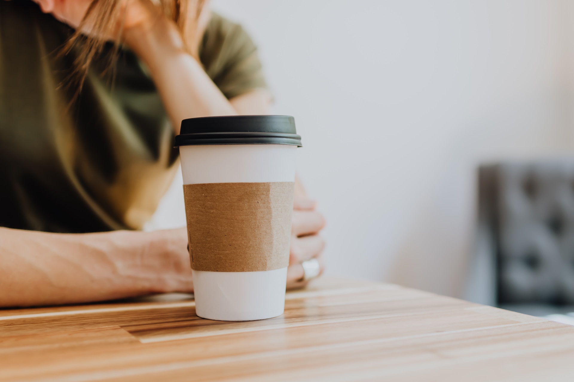 Image of woman at desk with a take-out coffee cup in front of her